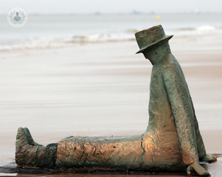 escultura hombre sentado en la playa