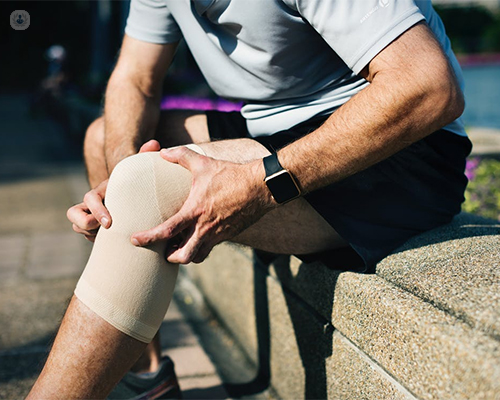 Hombre sujetándose la rodilla con dolor - by Top Doctors
