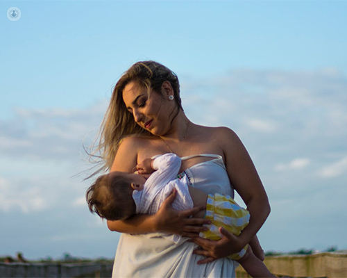 Chica amamantando a un bebé en el campo - depresión post parto - by Top Doctors