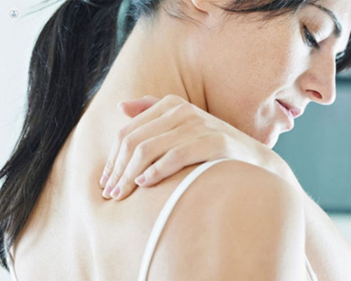 Mujer tocándose la espalda a la altura del cuello y las escápulas - botox para cicatrices de hernia discal - by Top Doctors