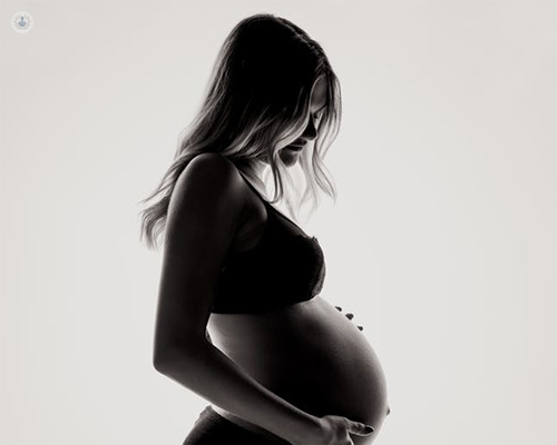 Mujer embarazada agarrándose la barriga - listeria y embarazo by Top Doctors